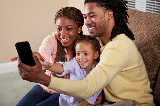 happy-mom-and-dad-with-young-child-looking-at-a-phone