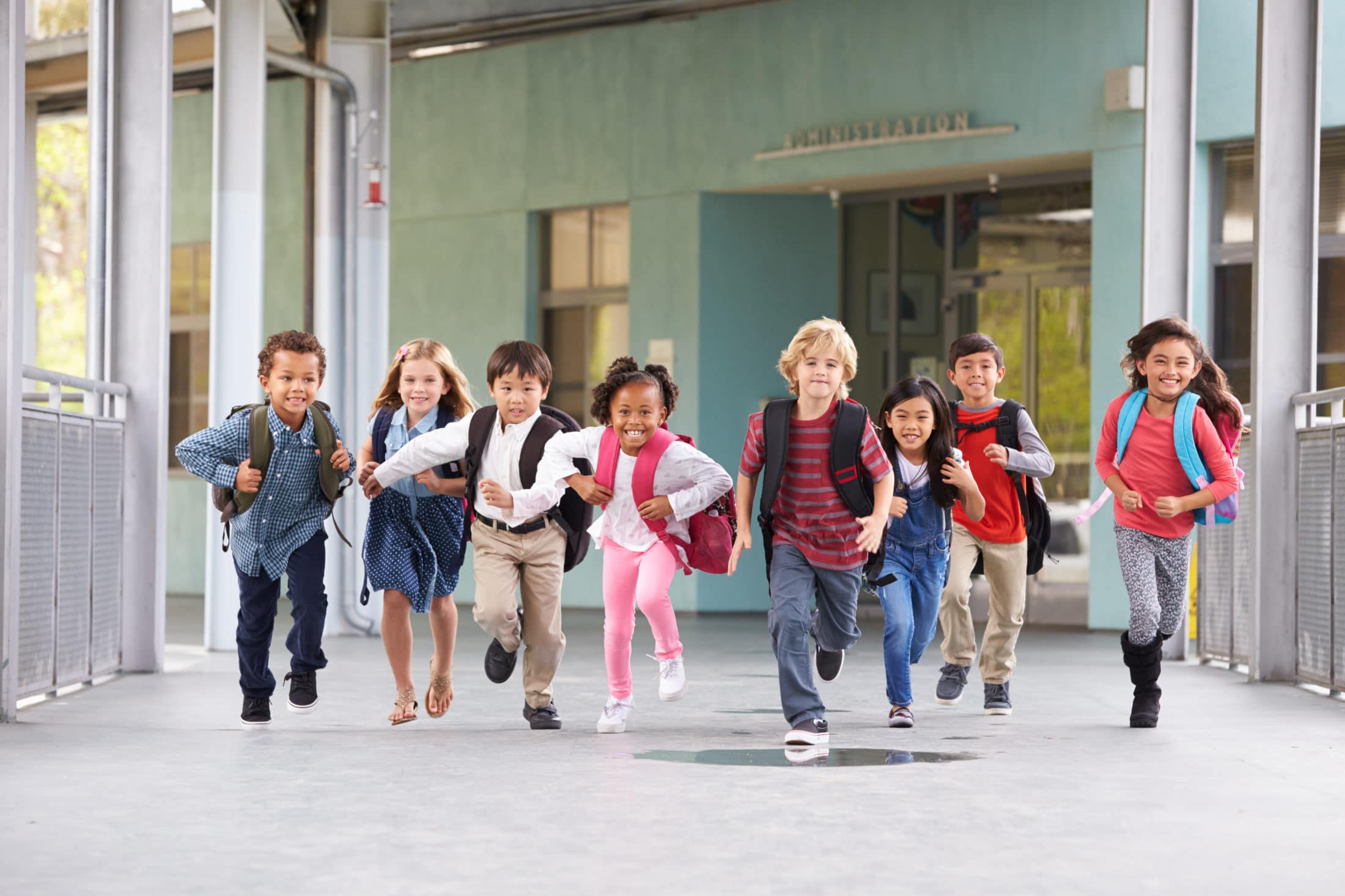 eight elementary children running down a school hallway